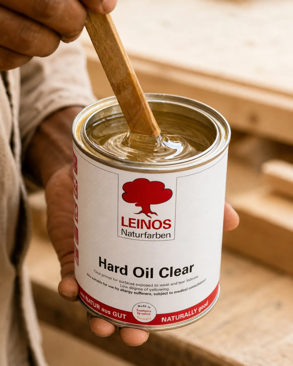 Indian craftsman stirring a tin of clear, colourless natural wood oil with a wooden stick