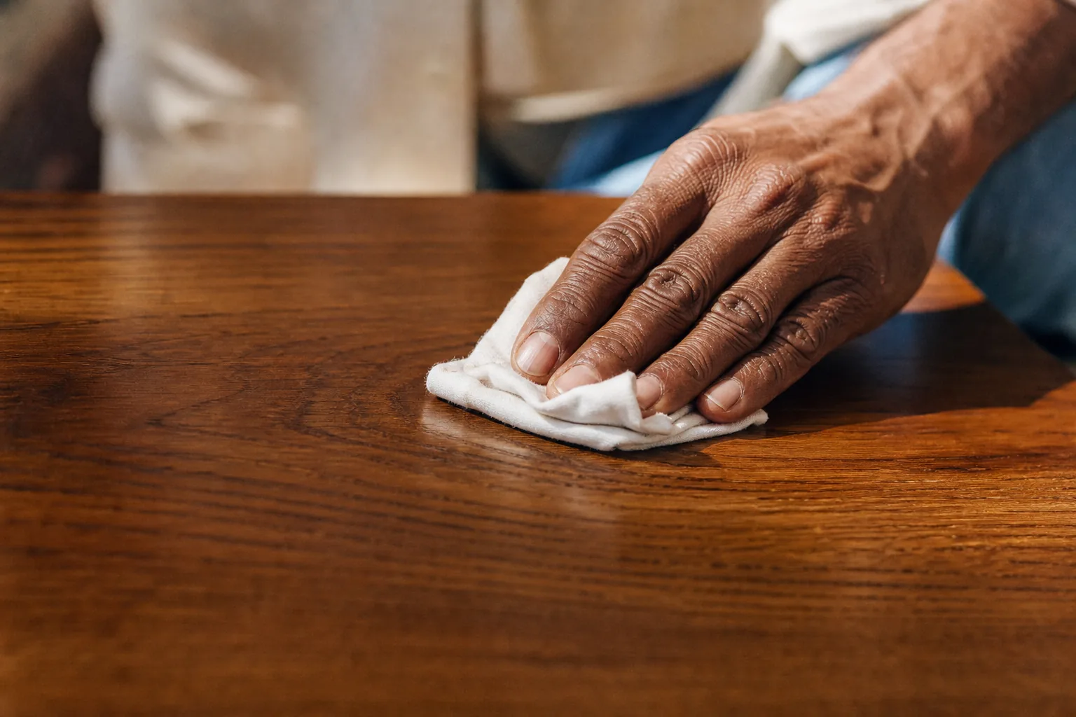 Indian craftsman wiping excess oil from an oiled oak floor with a folded cotton cloth