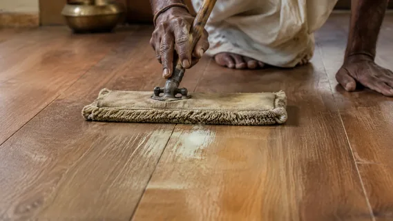A craftsman spreading a thin film of care oil across an oiled plank floor with a short-pile mop
