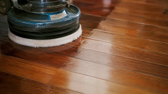 A white polishing pad burnishing an oiled timber floor to an even satin sheen