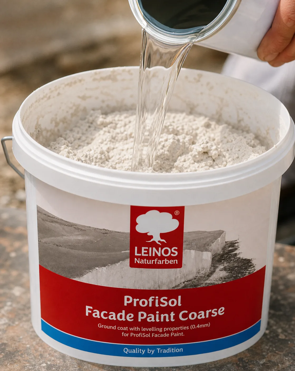 Pouring clear Profi-Fixativ from a canister into the branded LEINOS ProfiSol Facade Paint Coarse bucket to thin the coarse mineral paste