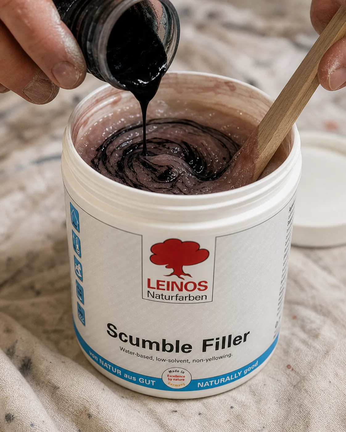 Pouring LEINOS 668 Pigment Concentrate into an open branded LEINOS 630 Scumble Filler tub and stirring the tinted translucent compound