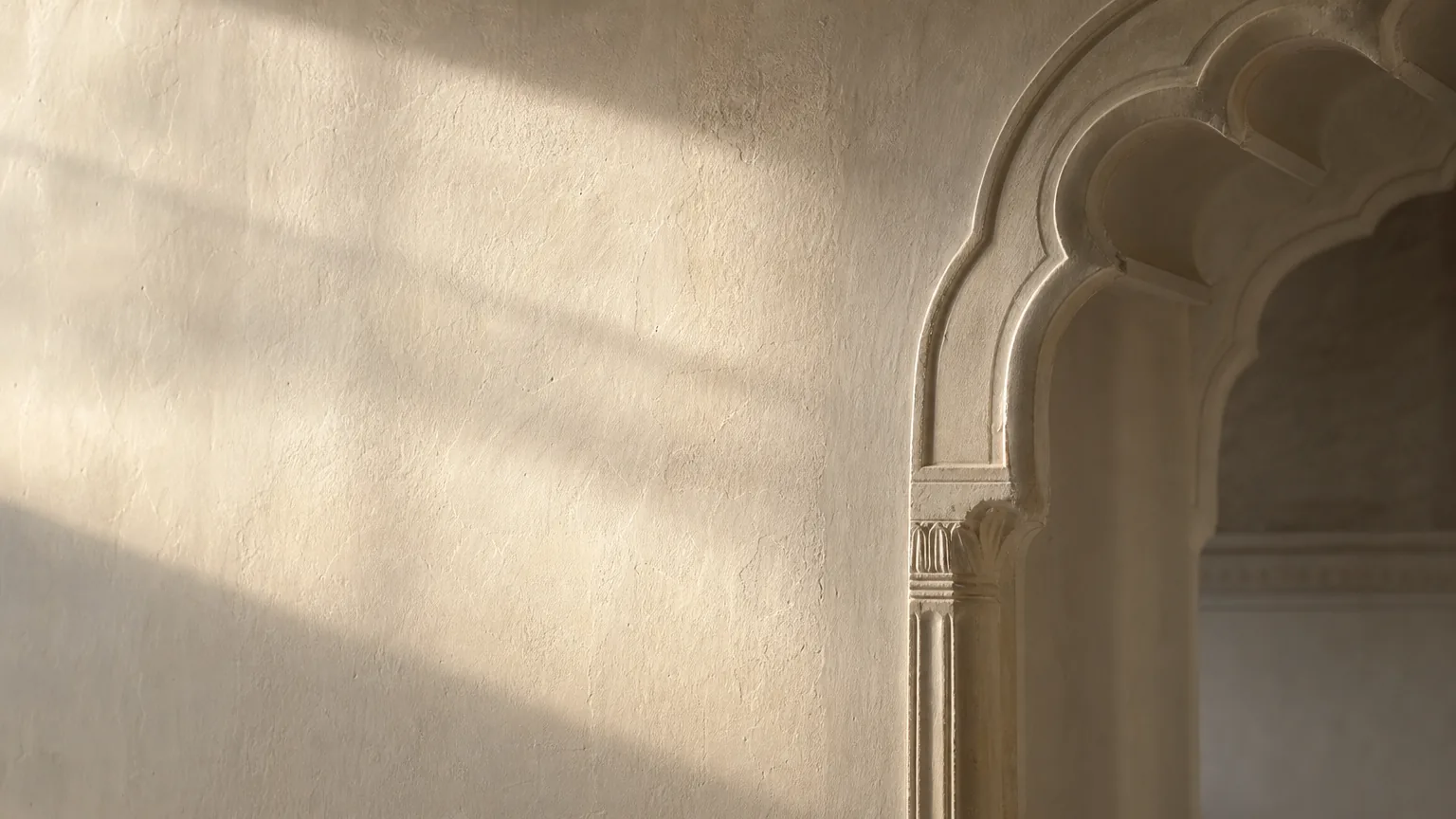 Finished limewashed heritage haveli interior wall in soft matt off-white with late-afternoon honey light raking across the cured surface