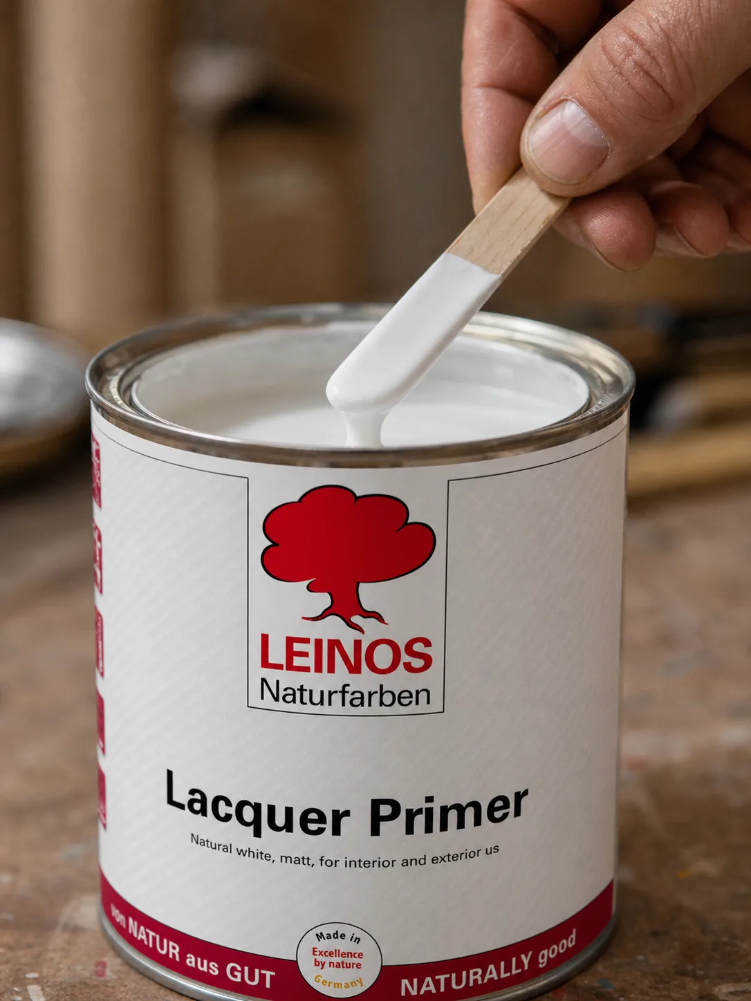 Stir stick blending matt natural-white primer inside an open branded LEINOS 810 tin