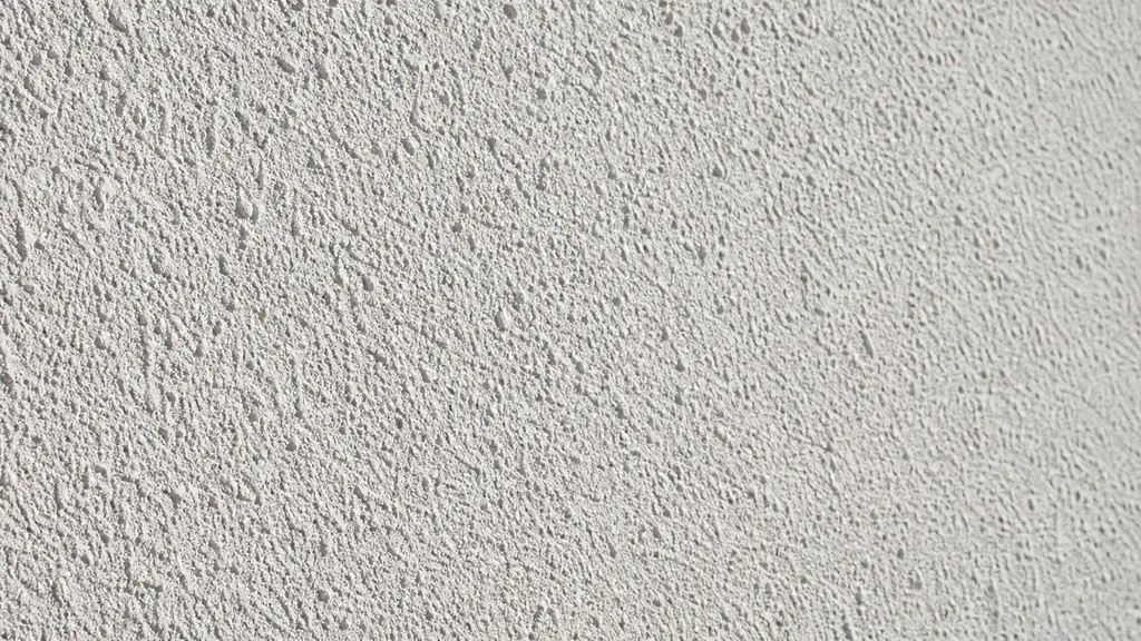 Extreme close-up of a dried natural-white primed wall showing a fine-grained rough matt key texture in raking light