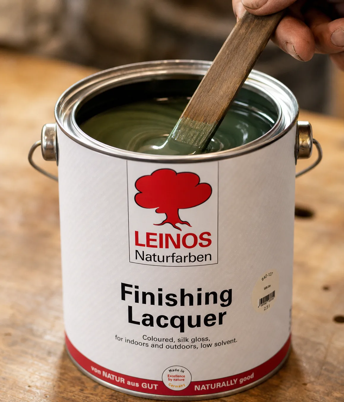 Stir stick blending fir-green silk-gloss lacquer inside an open branded LEINOS 840 tin