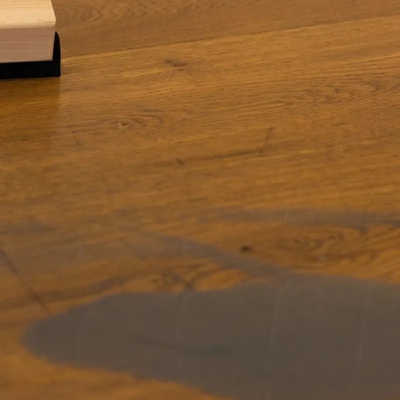 A spread of care oil resting on a section of oiled timber floor