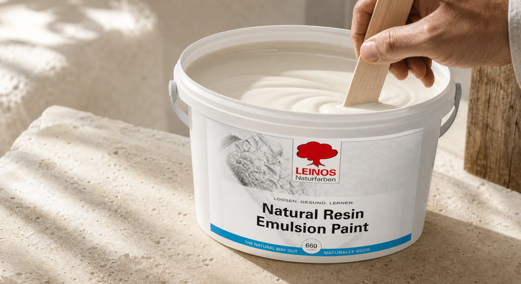 Hand stirring a host paint can with a clean mixing paddle, side daylight on the rim