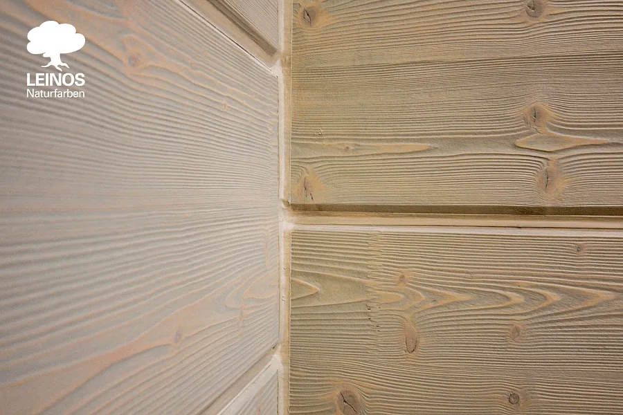 Close-up of brushed pine texture — recessed wash-coloured wood between proud hard grain ridges holding original pine tone.