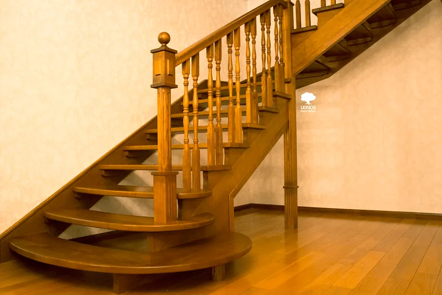 Wide view of the staircase under raking window light — lathe-turned profile clearly defined across the run.