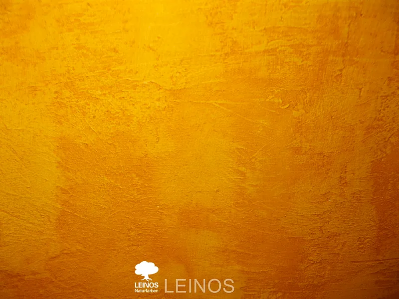 Close-up of the yellow wall surface — subtle hand-applied tonal variation reading 'painted by hand' under Rajasthani daylight.
