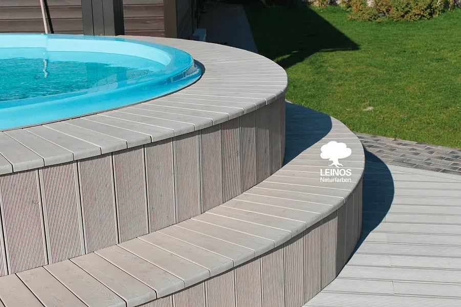 Radial deck board pattern around the pool — uniform grey tone, wood grain visible through the open-pore oil.