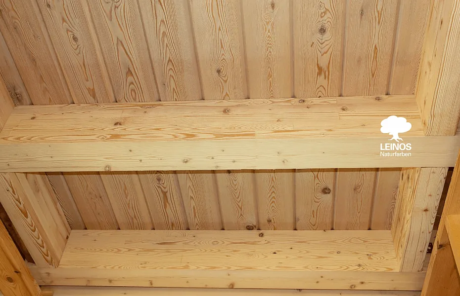 Detail of an exposed pine beam — warm vanilla register with the grain reading clearly through the oil.