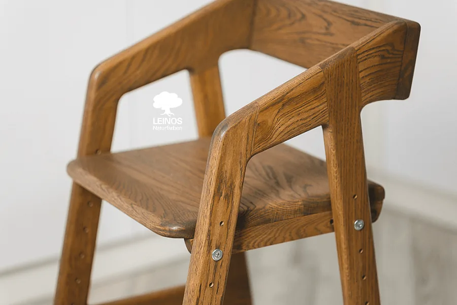 Detail of the seat adjustment slot — deep brown stain with oak grain still legible under the oil sealer.