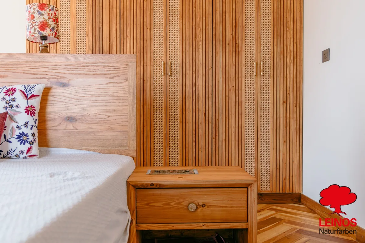 Wide bedroom view — cabinets and wall panels reading as one continuous handcrafted material.