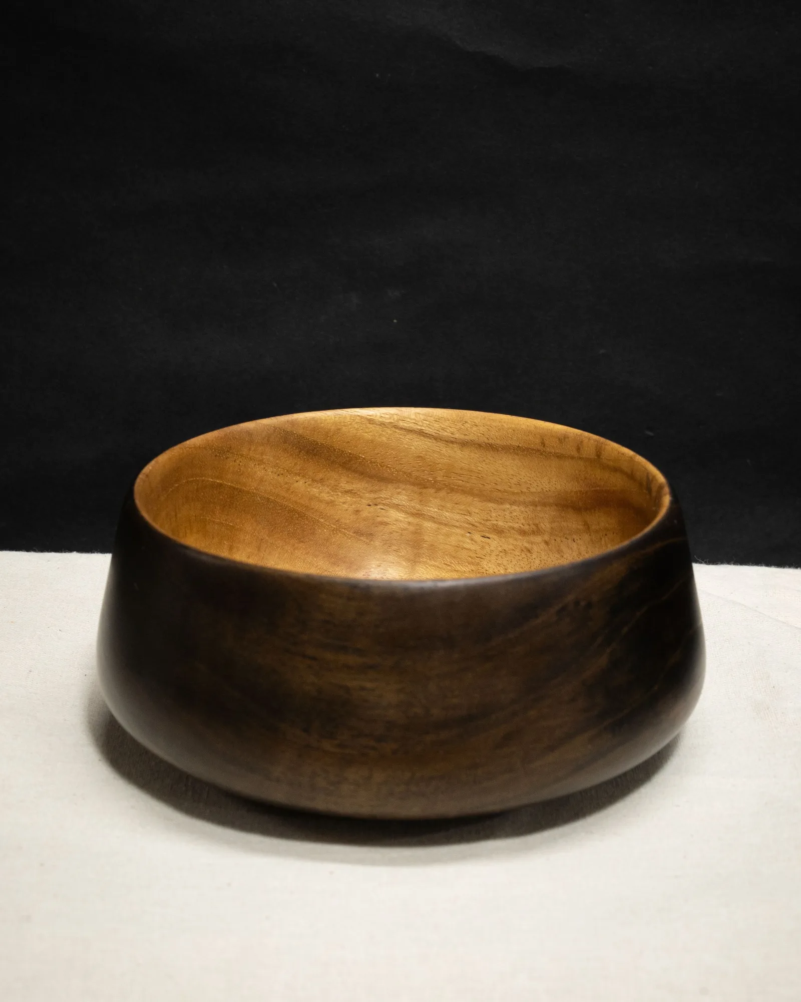 A turned teak bowl by Kathkani Studio with a fully ebonised black exterior and a warm natural interior, finished in LEINOS Interior Hardwax Oil 290 — satin grain catching the light.