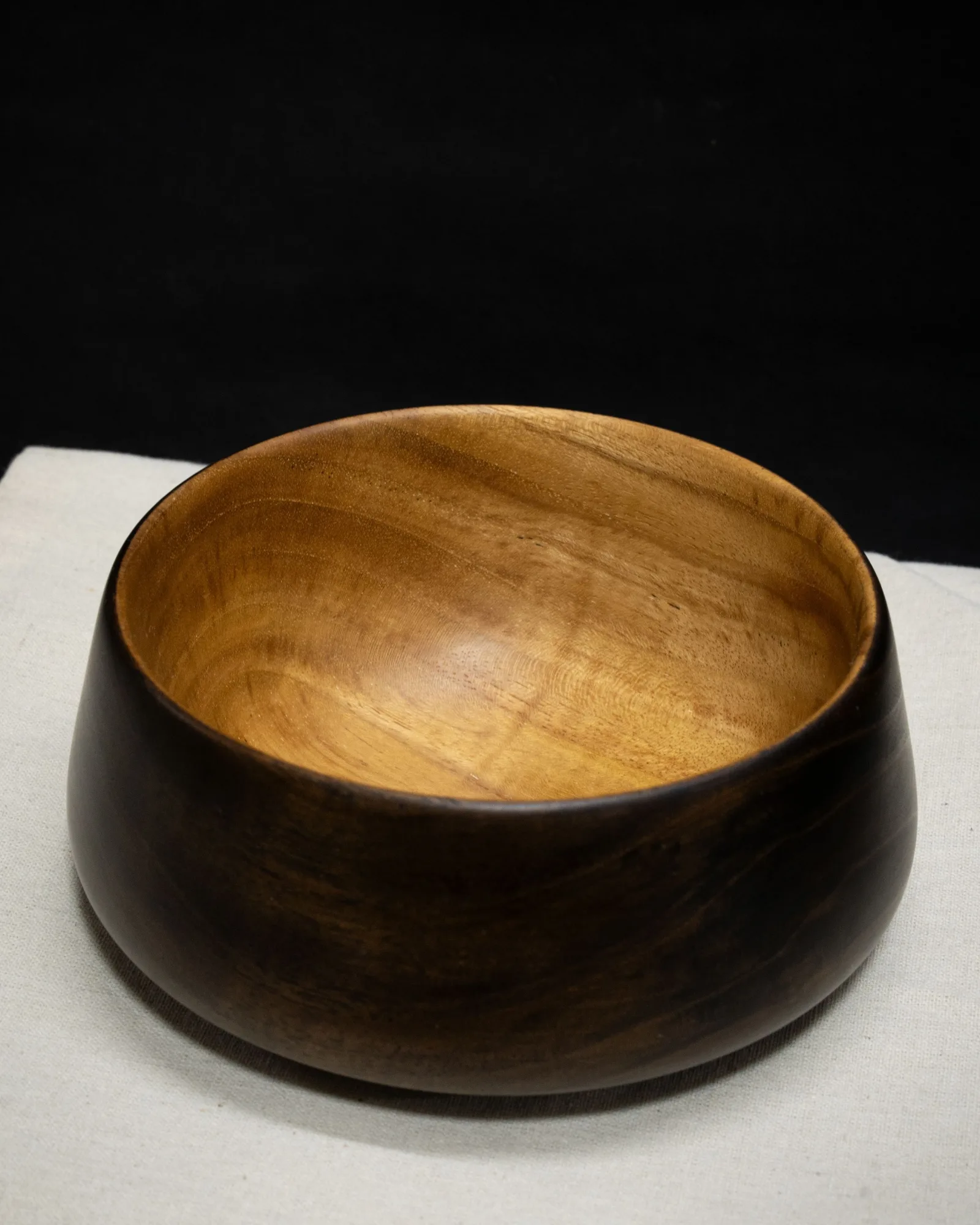 Looking into a turned teak bowl by Kathkani Studio — the warm, open-pored interior glowing under its LEINOS Interior Hardwax Oil 290 finish, framed by the ebonised black rim.
