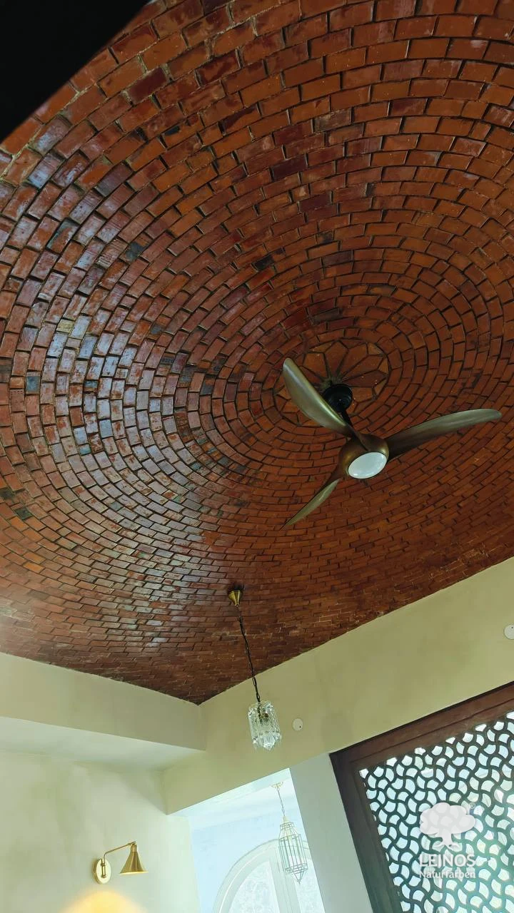 A spiral vault of exposed terracotta brick laid in concentric rings into a shallow dome, a brass ceiling fan at its centre — the brickwork sealed in LEINOS Stone & Concrete Oil 254, an open-pore oil that keeps the natural terracotta red.