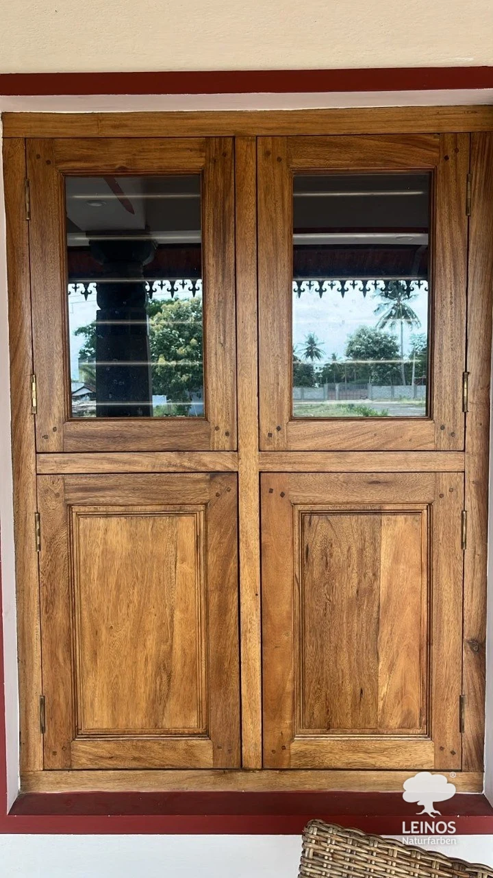 Glazed teak windows with panelled lower sashes in the same Bengaluru home, finished in LEINOS Interior Hardwax Oil 290 — the grain visible under a low-sheen open-pore surface.